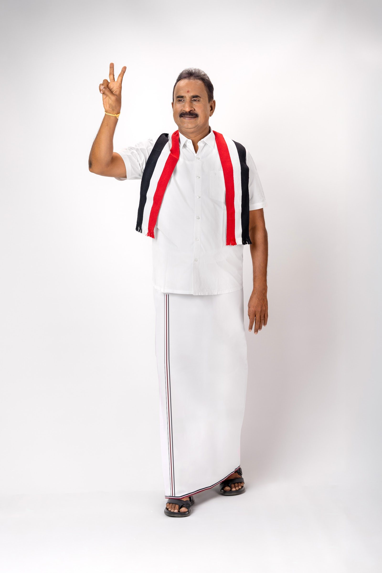 S. P. Velumani raising a victory sign in the party scarf