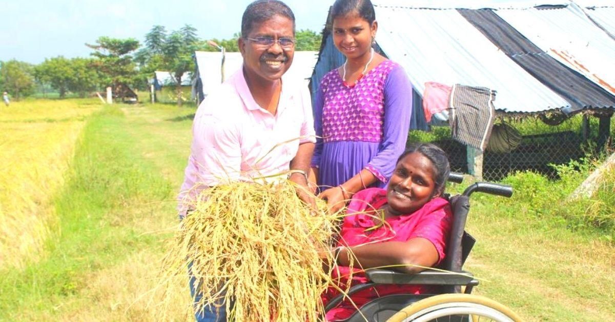 A woman in a wheelchair holding harvested paddy with her family in a field